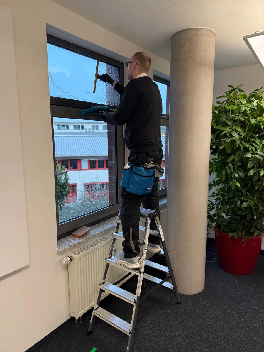 Fensterreinigung innen: Mitarbeiter von H2 Clean reinigt in einem Büro in Tübingen ein Fenster mit dem Abzieher