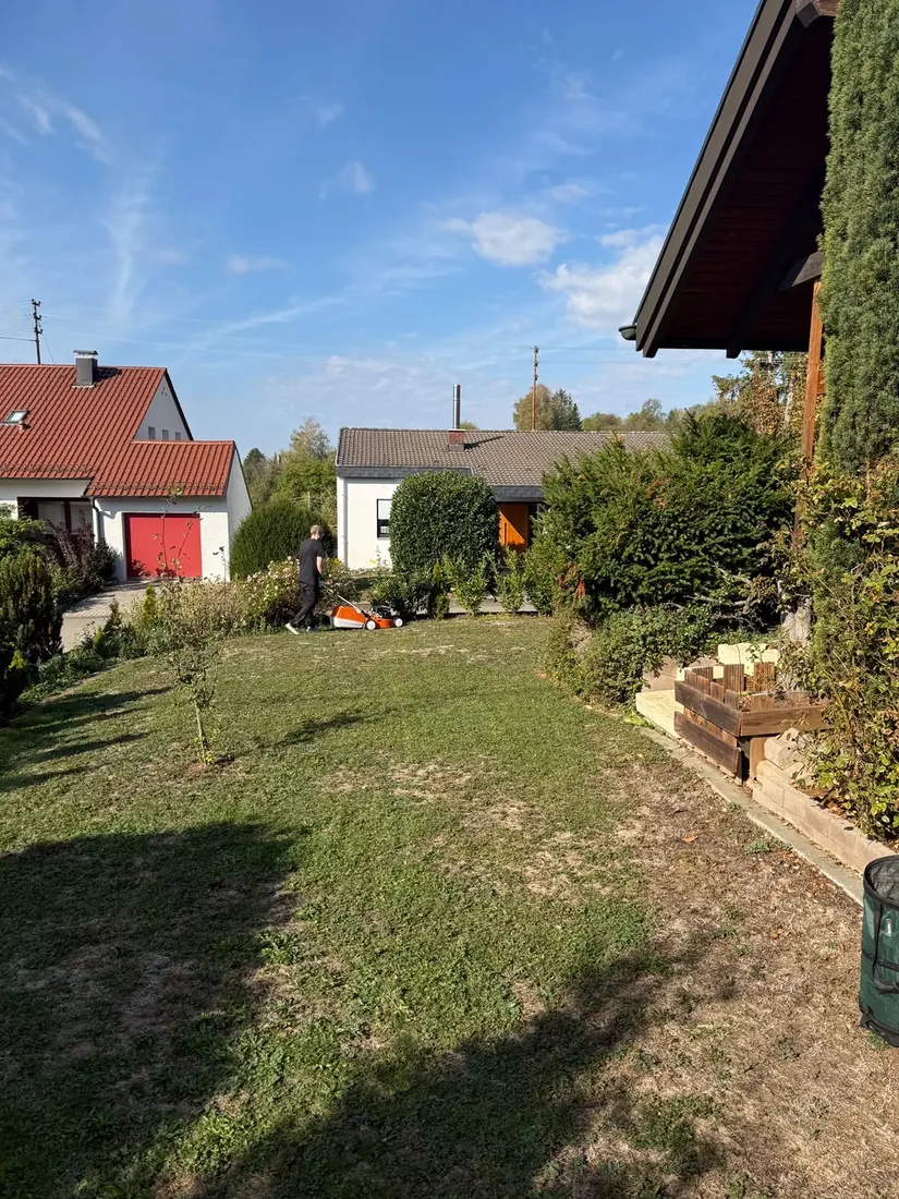 Außenpflege bei der Objektbetreuung: Mitarbeiter von H2 Clean mäht den Rasen im Garten eines Hauses im Verkauf