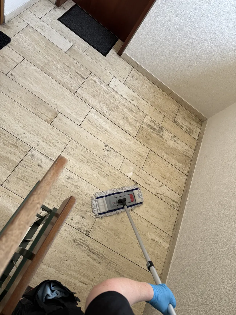Treppenhausreinigung in Reutlingen: Wischen des Treppenpodests mit Flachmopp in einem Mehrfamilienhaus